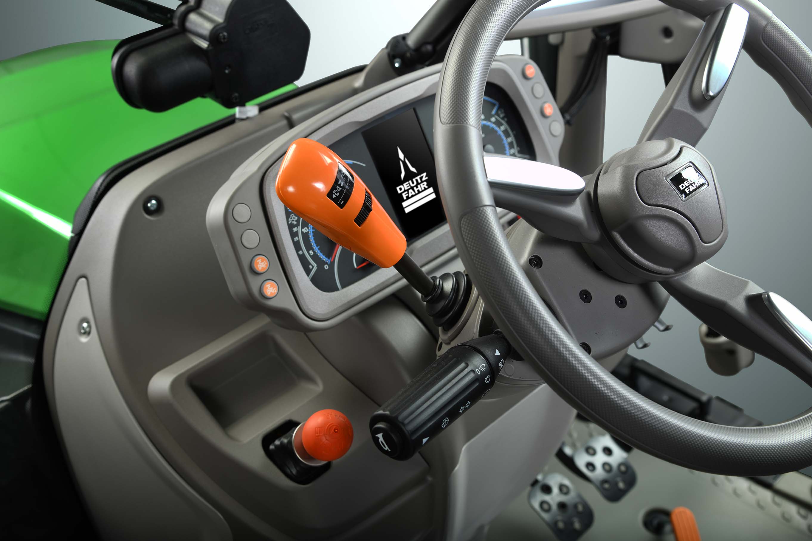 Binnenzicht van een Deutz-Fahr cabine, met het stuur, het dashboard en de oranje bedieningshendel van de versnellingsbak.