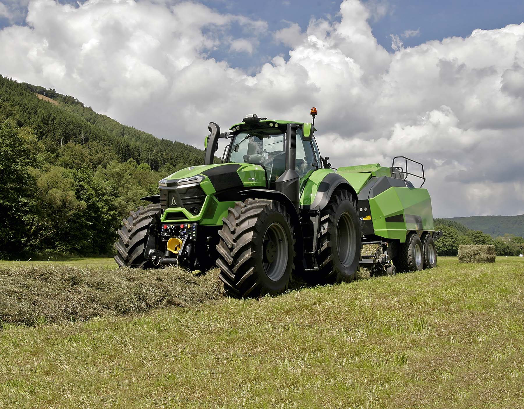 Deutz-Fahr trekker met een persmachine, werkend op een landbouwveld onder een heldere lucht, illustrerend slimme landbouwtechnologie.
