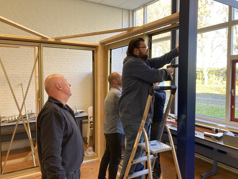 Man op ladder aan het boren in een gevel