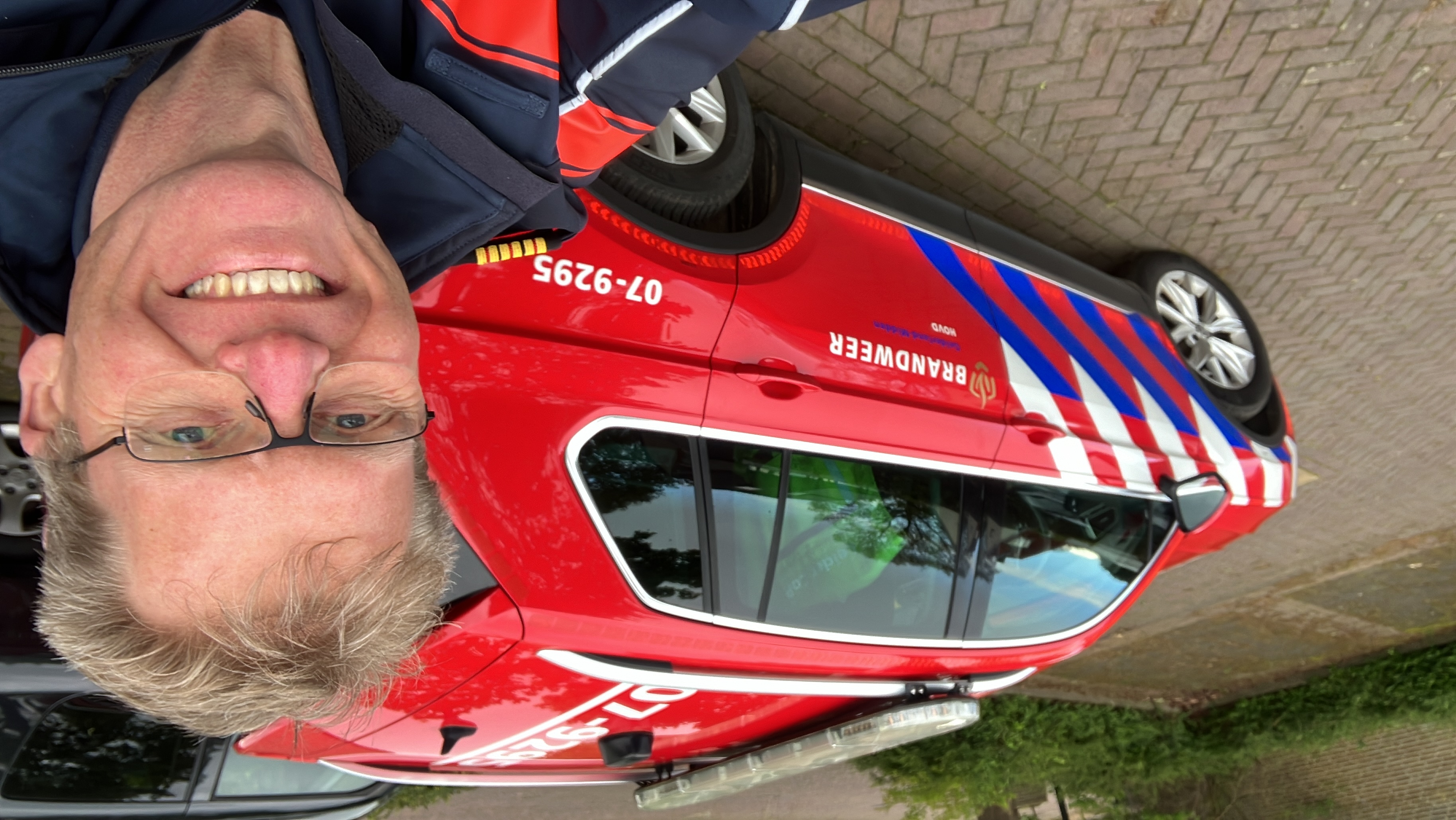 Jan Pieter Duhen maakt een selfie naast een rode brandweerauto van Brandweer Midden-Nederland.