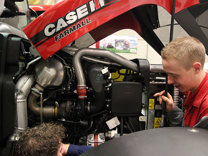 Twee leerlingen bekijken motor van tractor