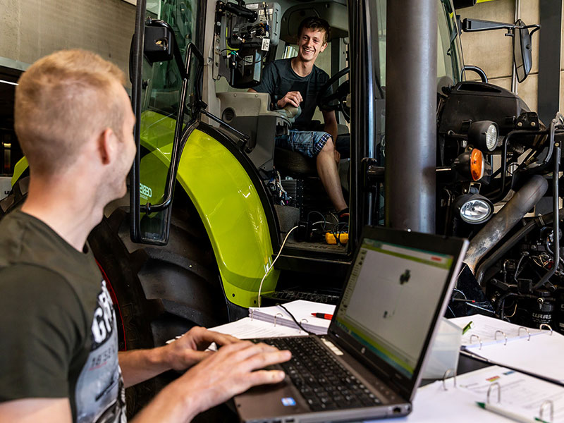 Leerling achter een laptop en een in tractor