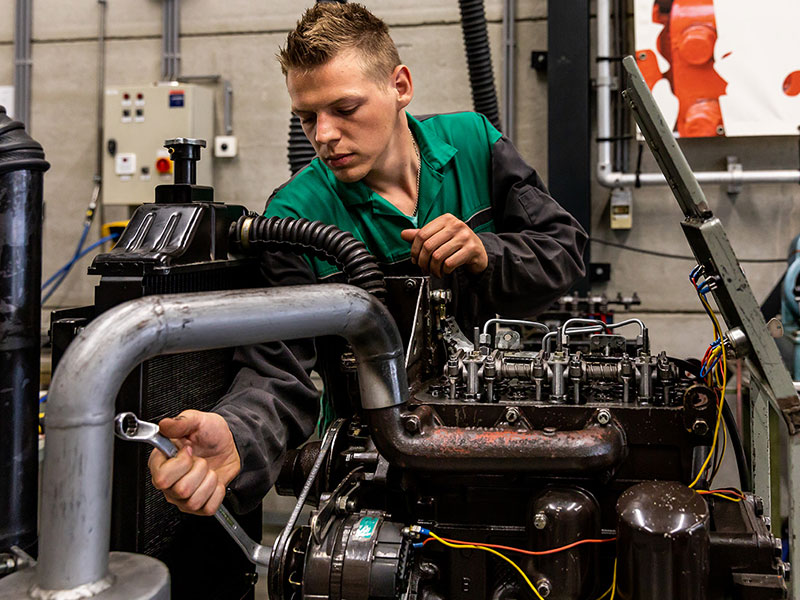 Leerling sleutelt aan tractor Deutz Farh