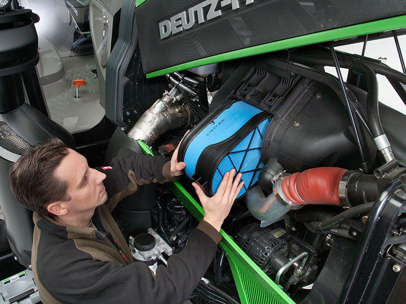 Man plaatst luchtfilter in Deutz Farh tractor