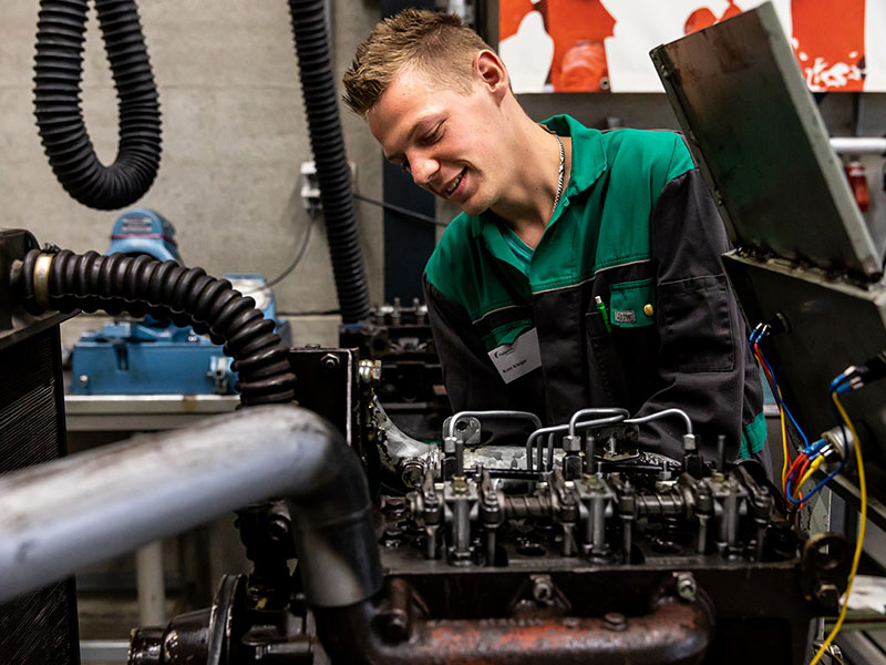 Leerling aan het werk met motor van tractor