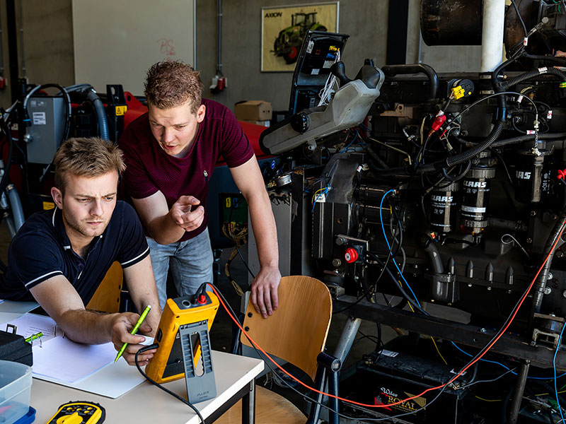 Twee leerlingen met een tractor motor