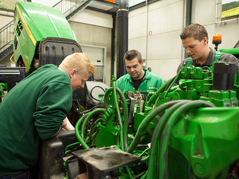 Drie leerlingen werken aan een John Deere