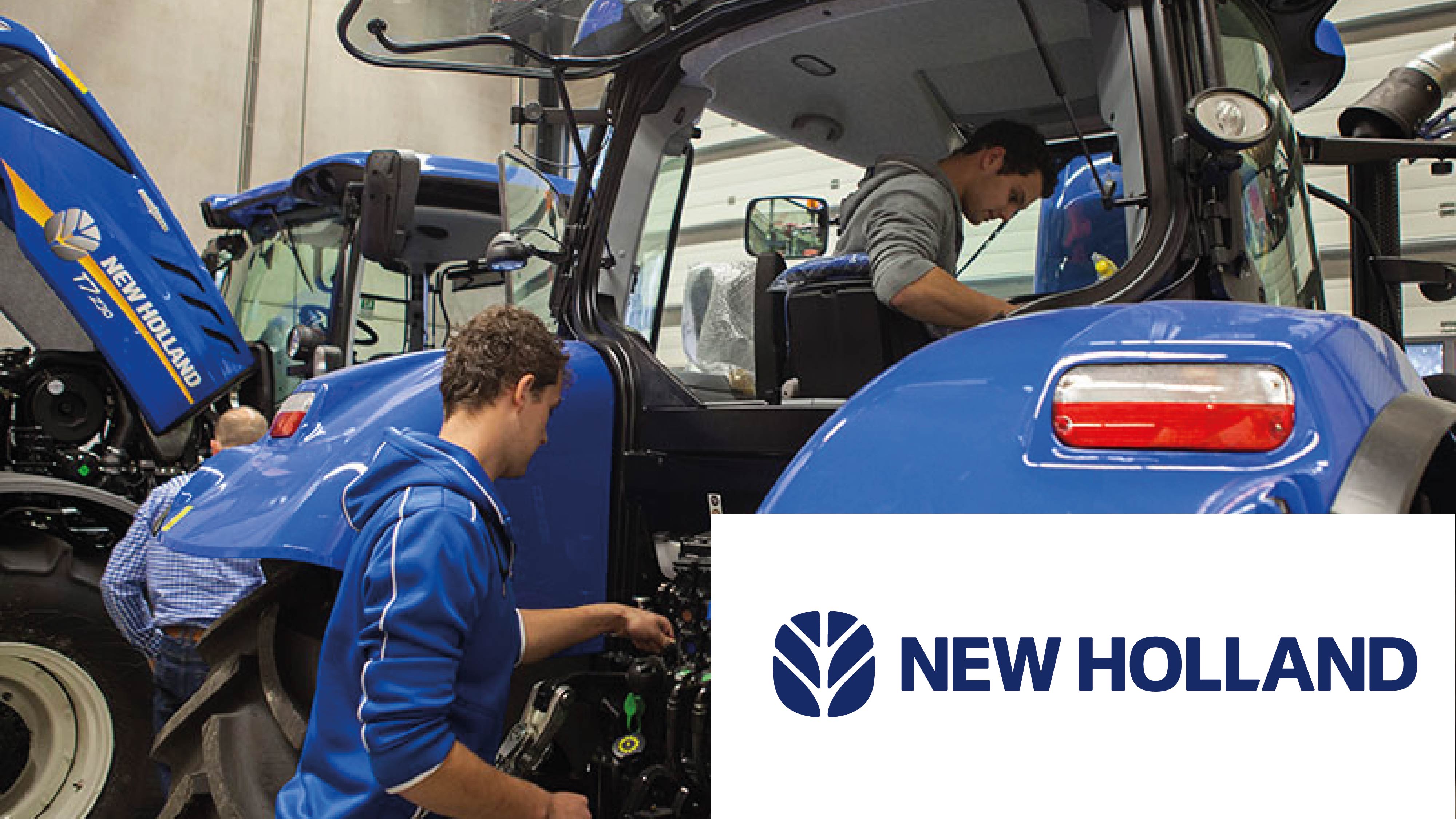 Twee monteurs werken aan een blauwe New Holland tractor in een werkplaats, met het New Holland-logo en bedrijfsnaam op de voorgrond.