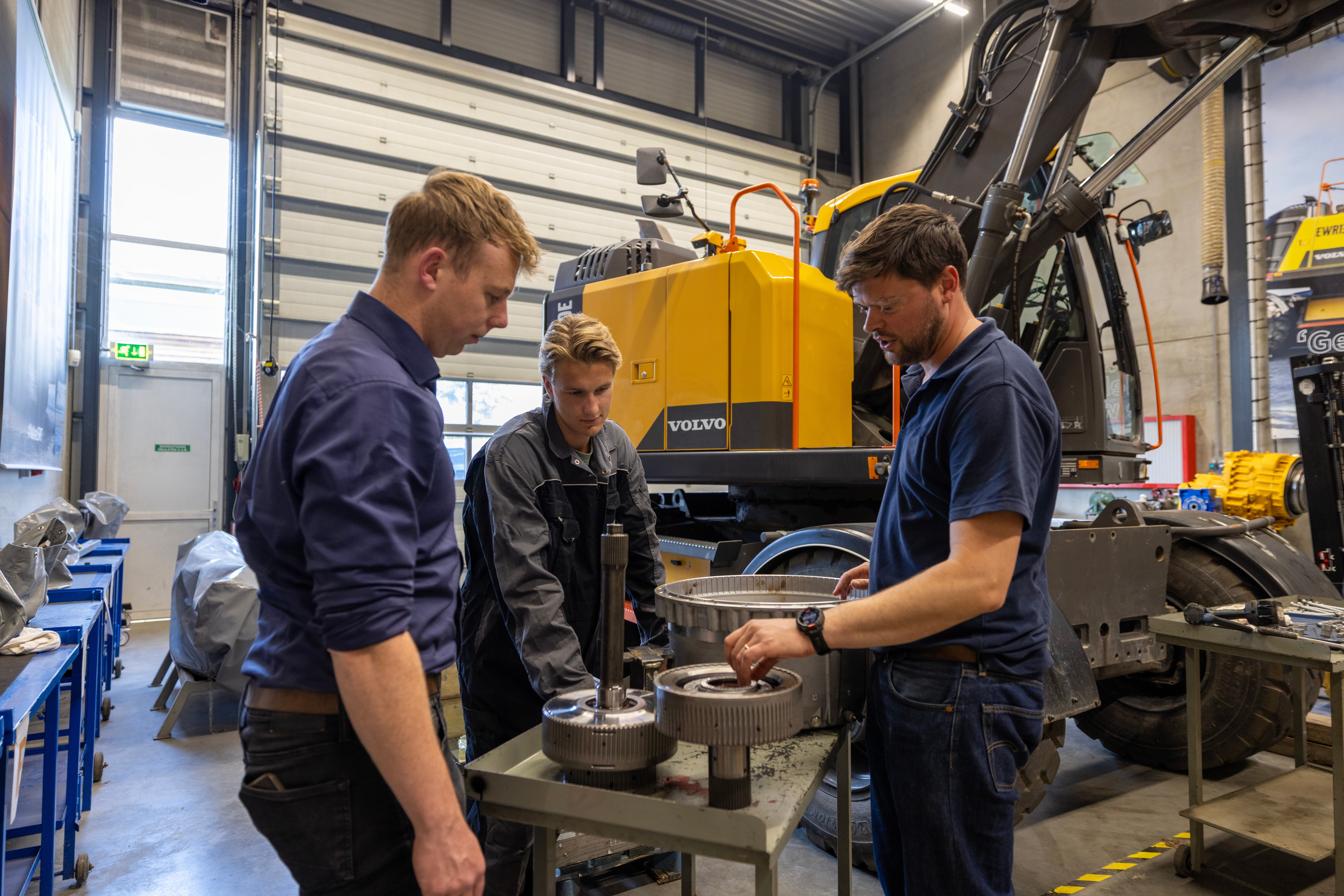 Drie monteurs aan het werk bij een Volvo grondverzetmachine